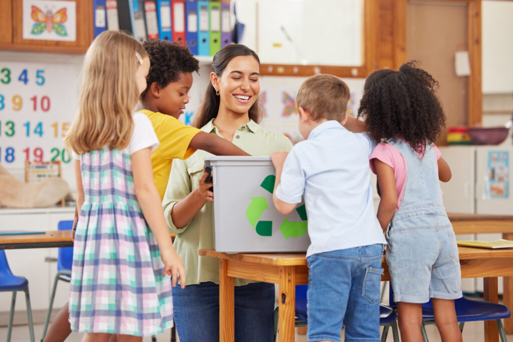 a person and kids around a recycle bin