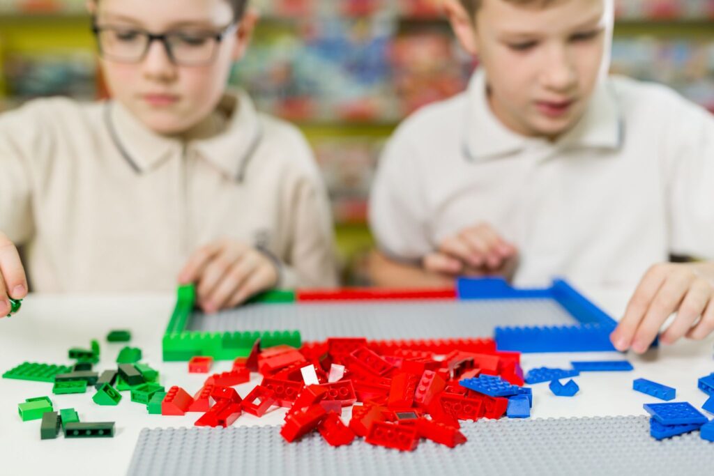 Children play in the designer at the table. Two boys play together with colored plastic blocks in the gaming center, school.